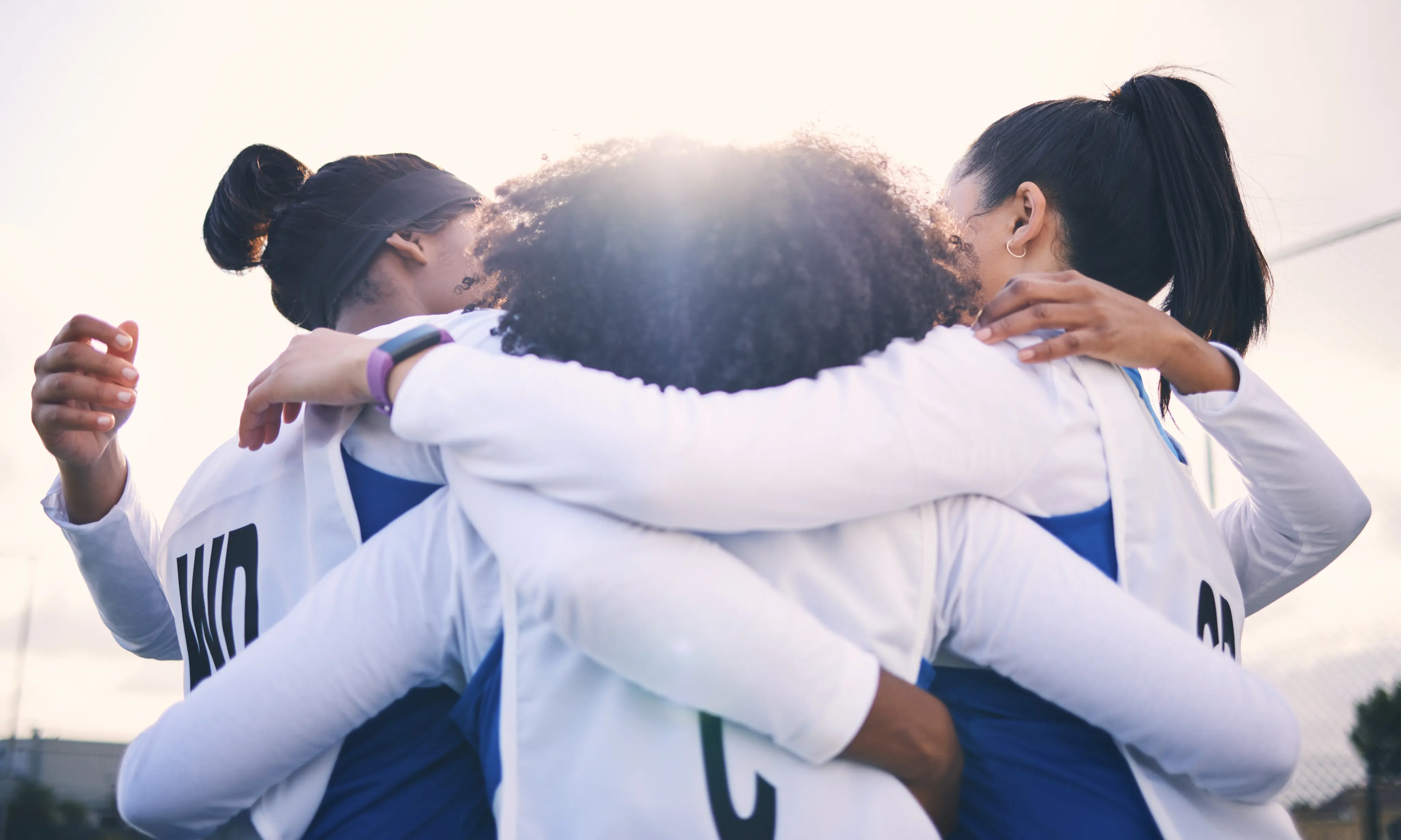 Women athletes in a team huddle, representing collaboration and joint decision-making in sports organizations.