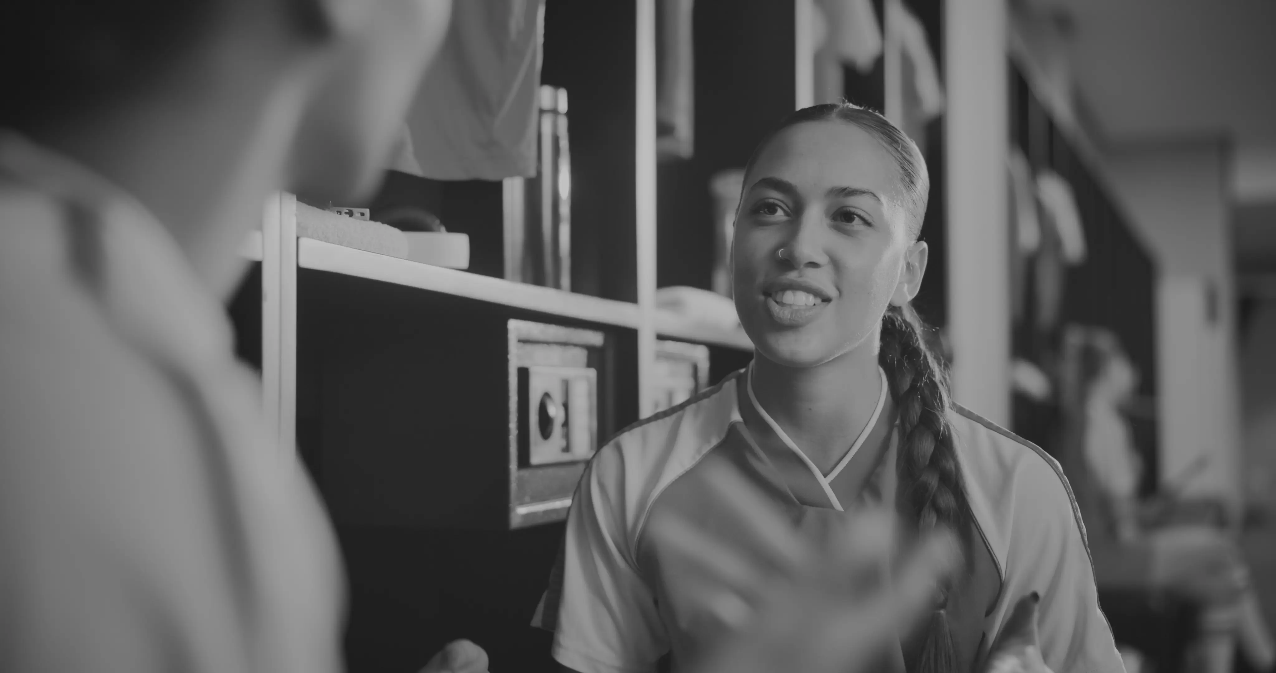 Women athletes in a locker room discussing strategy, representing teamwork in women’s sports organizations.