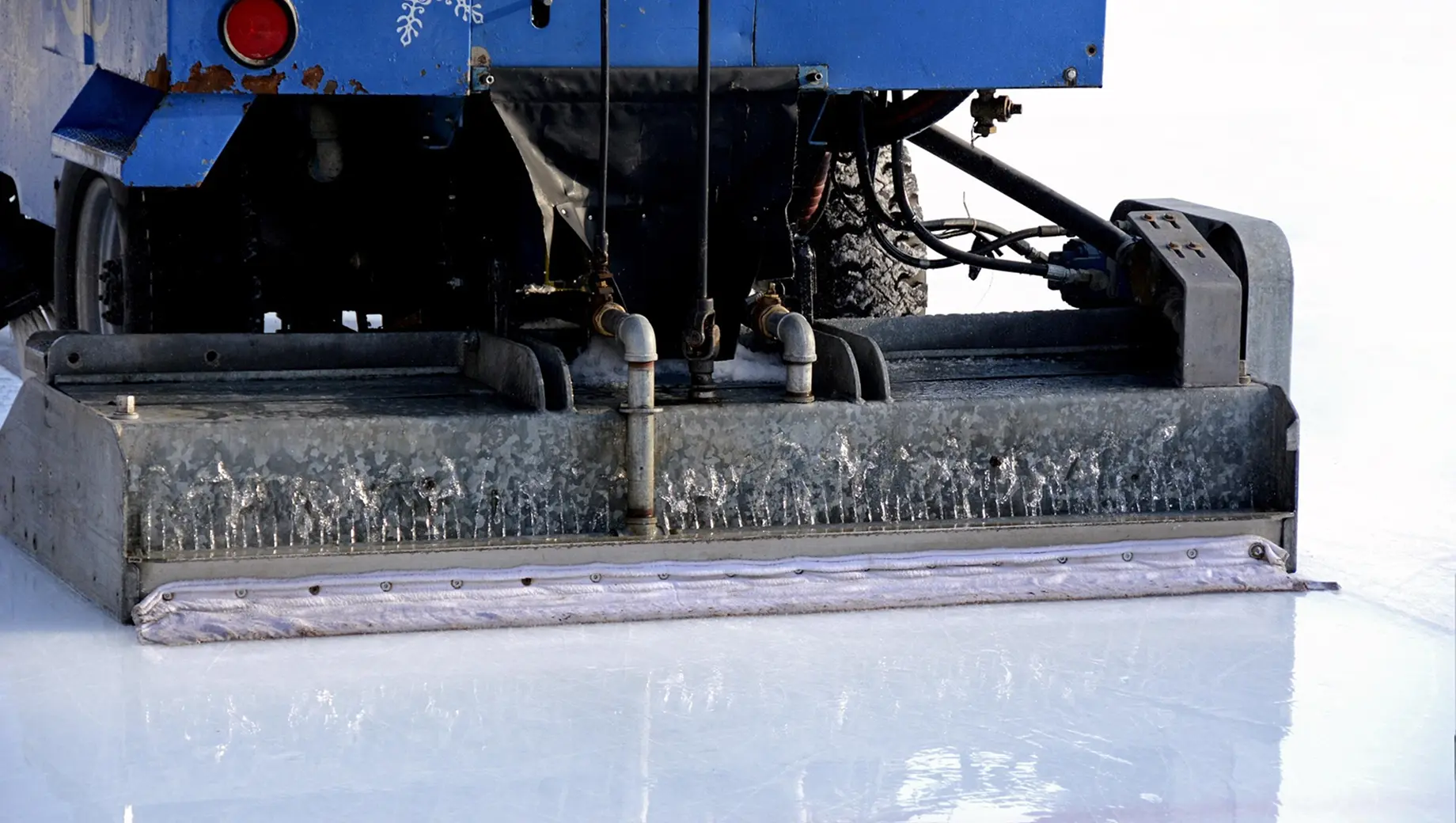 Ice resurfacer smoothing an indoor rink, illustrating artificial ice technology used in Winter Olympics venues.