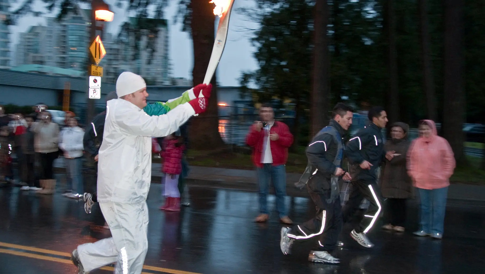 Olympic torchbearer carrying the flame during a relay, representing the logistics and event operations behind the Winter Olympics.